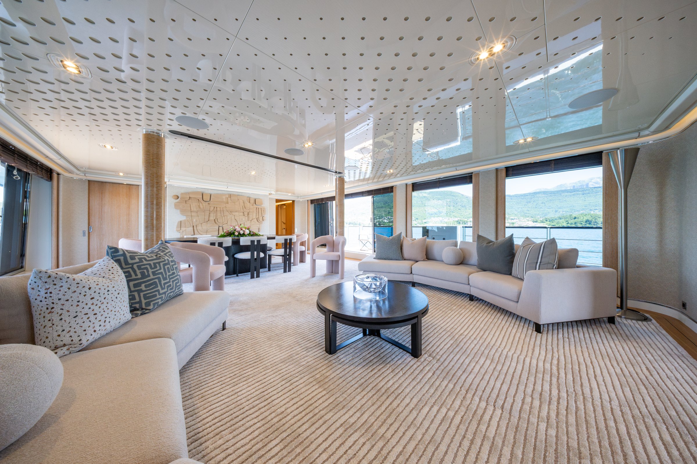 Main salon of AQUARIUS with pale seating and formal dining beyond