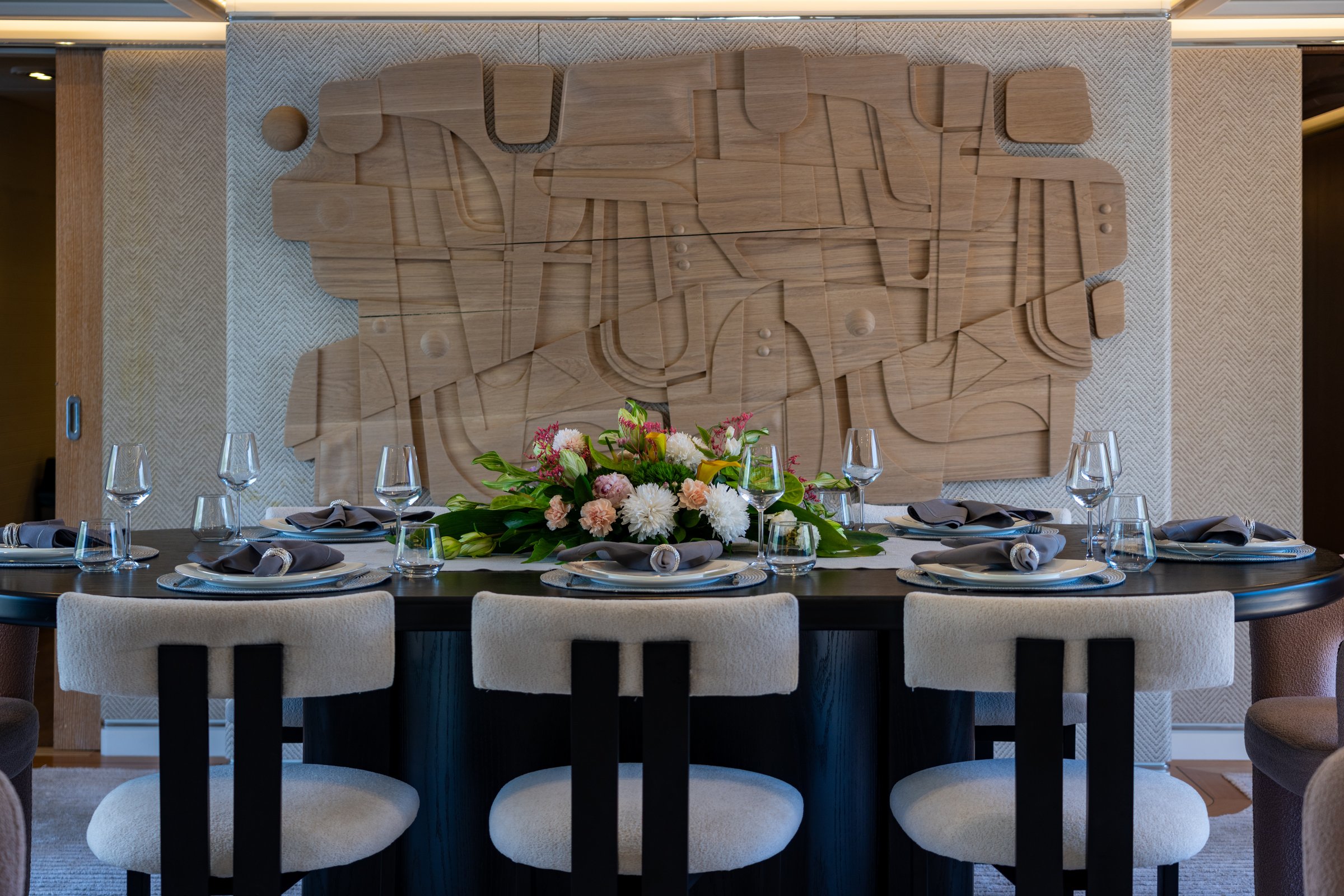 Formal dining table aboard AQUARIUS set for ten beneath a carved timber artwork