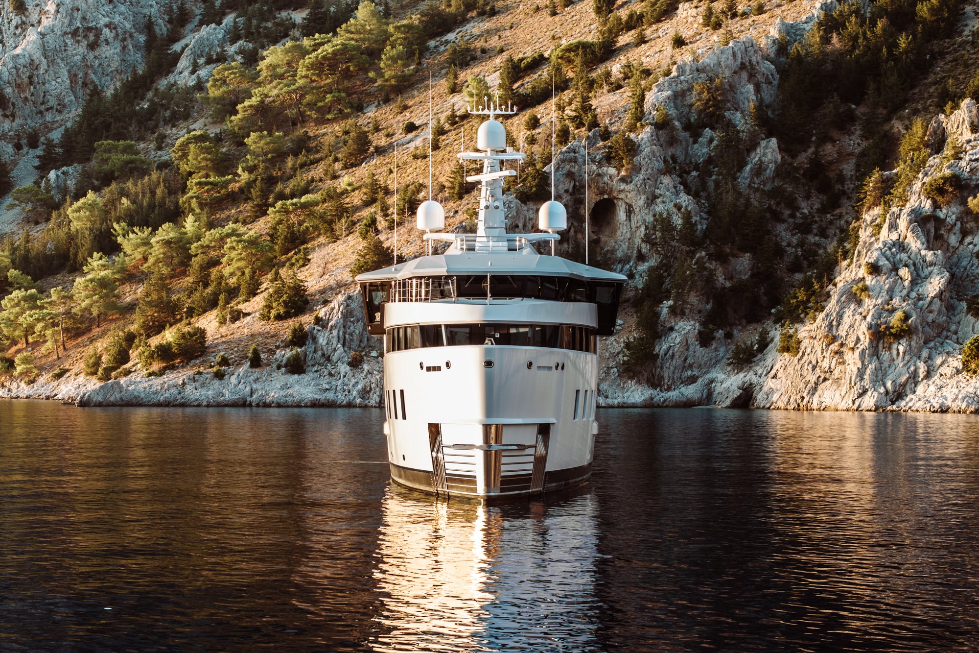 AFTER YOU — Bow view at anchor in a rocky bay at golden hour