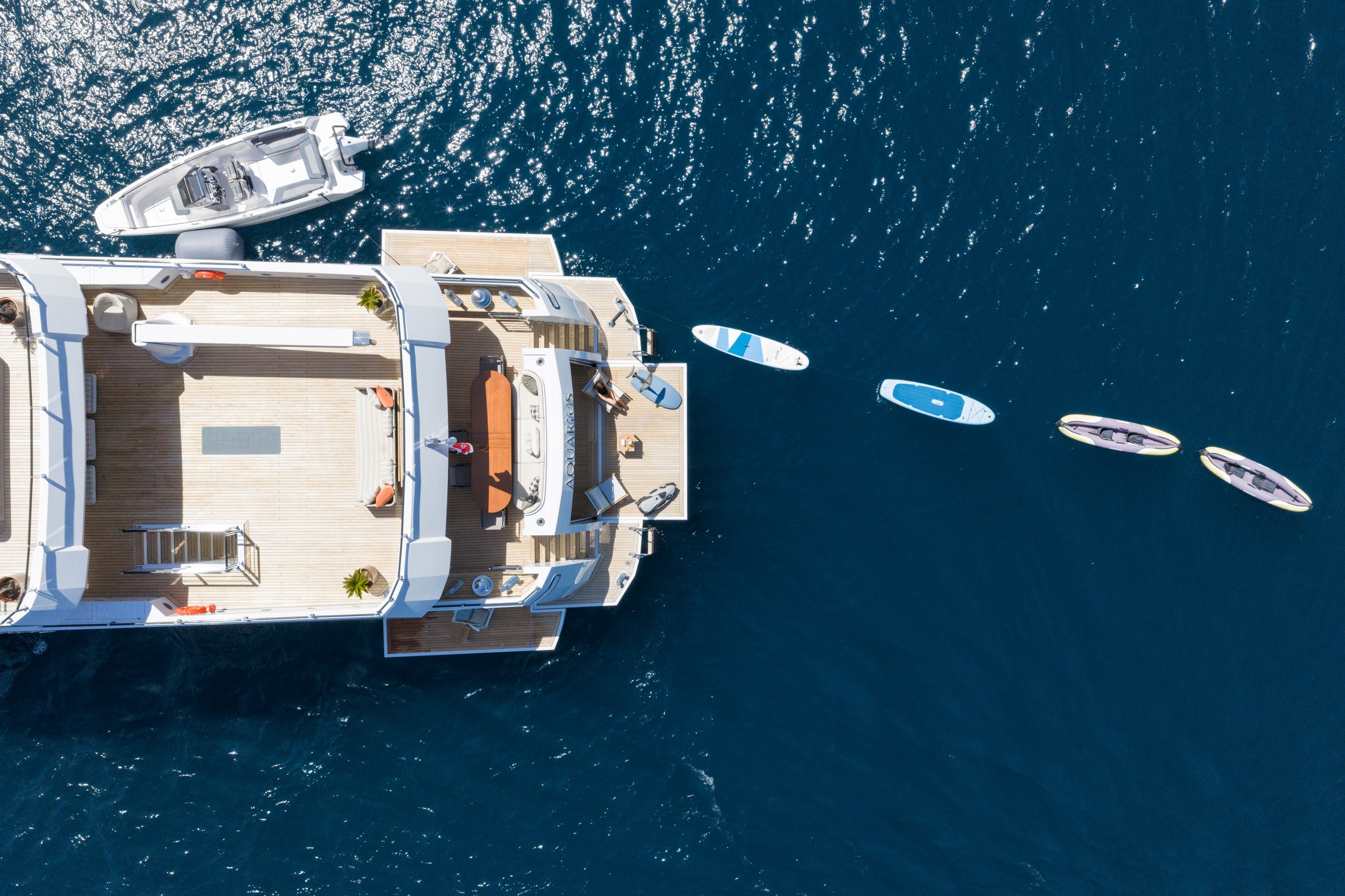 Overhead view of the aft decks of AQUARIUS with paddleboards and kayaks in the water