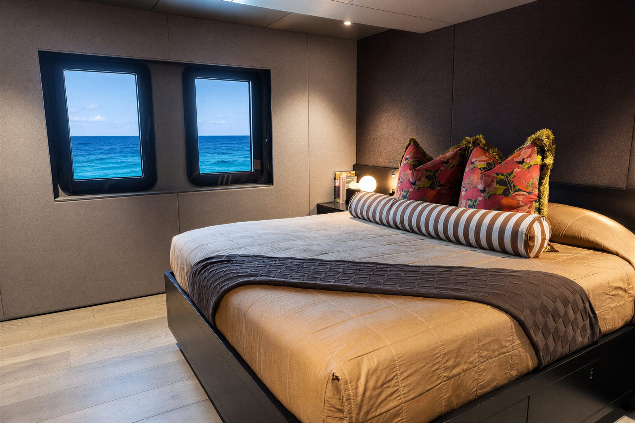 King guest suite aboard 2B with two square portholes framing open ocean