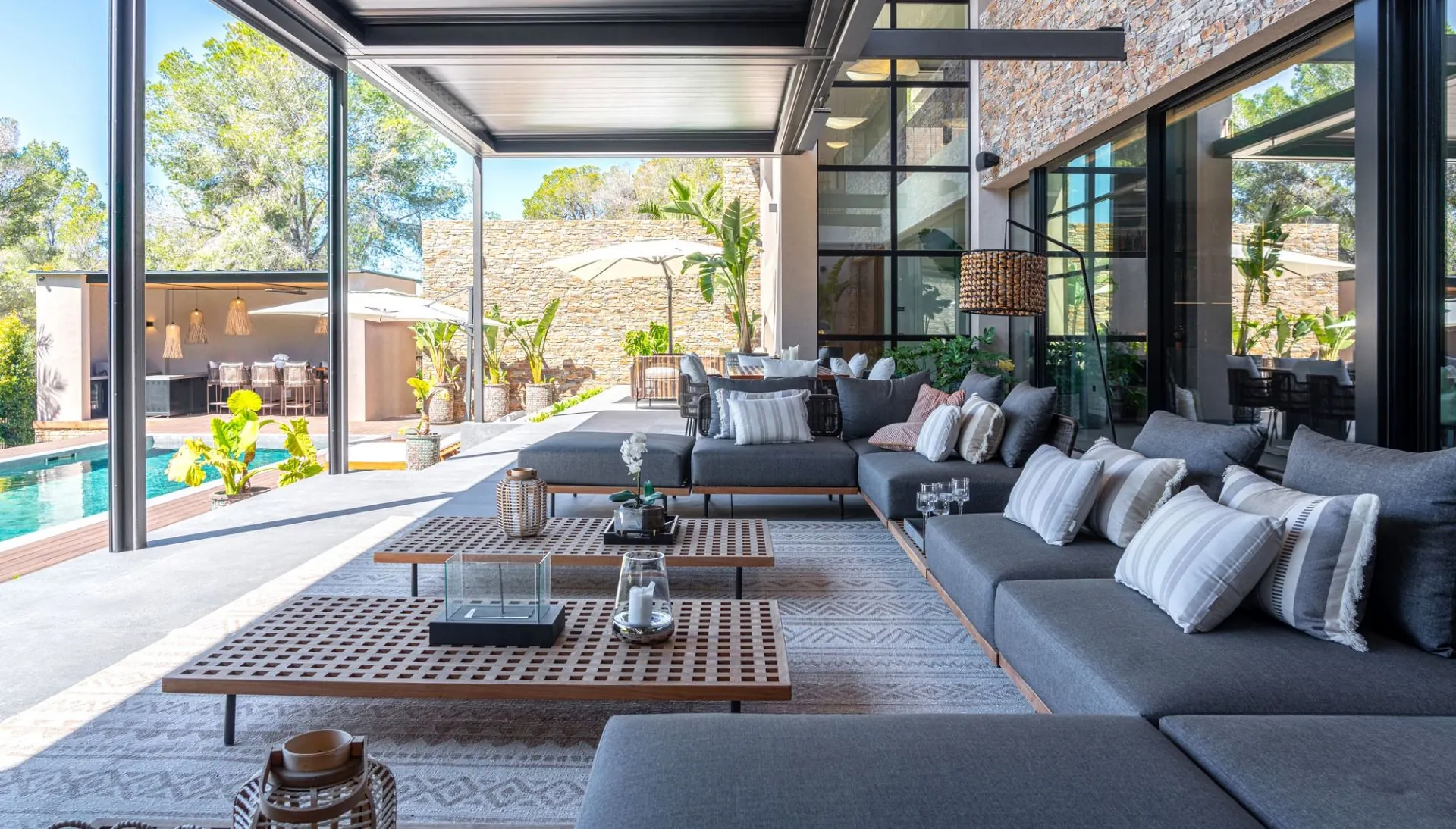 Covered outdoor lounge with sofas opening toward the pool at the Cala Vinyas villa