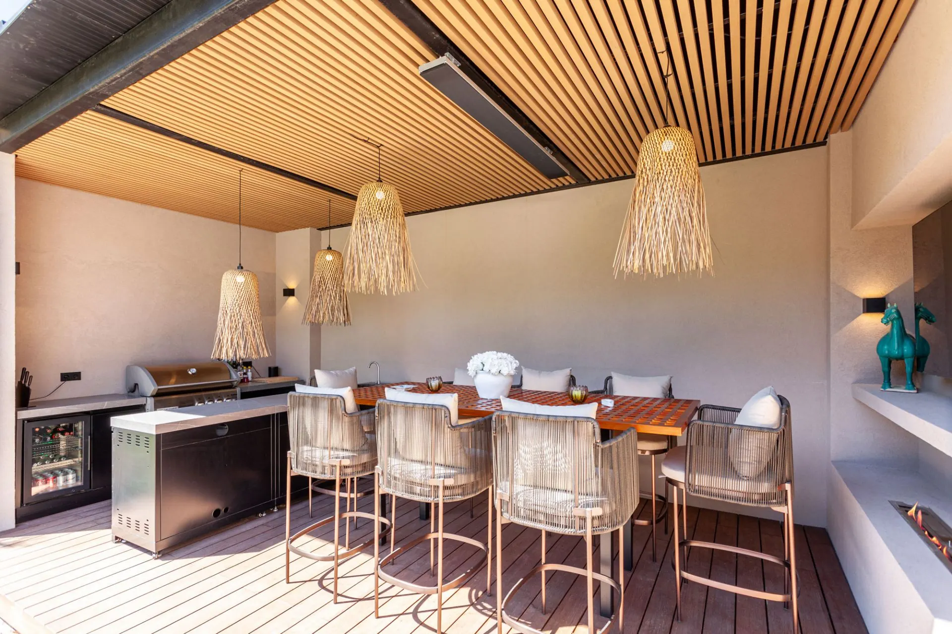 Covered outdoor dining table and built-in grill beside the pool at the Cala Vinyas villa