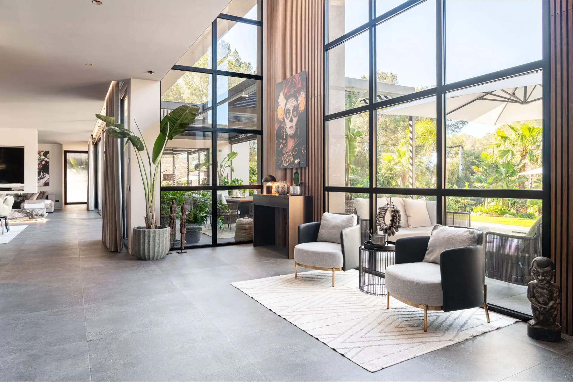 Dining table inside the Cala Vinyas villa, looking through floor-to-ceiling glass to the terrace and pool