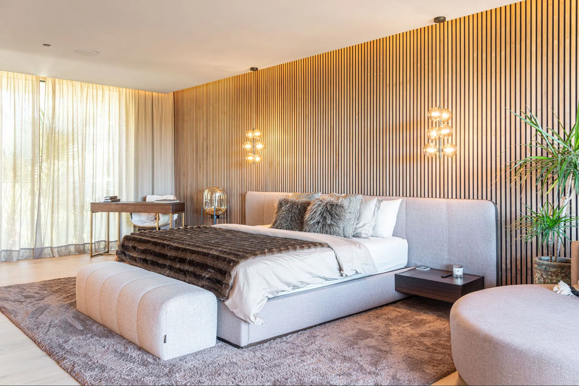 A bedroom in the Cala Vinyas villa, with the bed set against a timber-slat wall